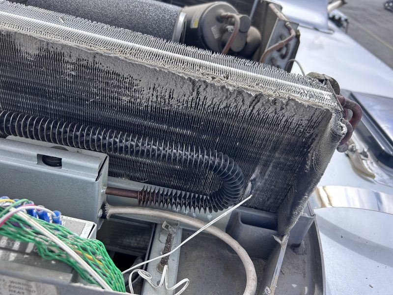 Dust-packed coil inside an RV rooftop air conditioner with the shroud removed, photographed during a Las Vegas service call